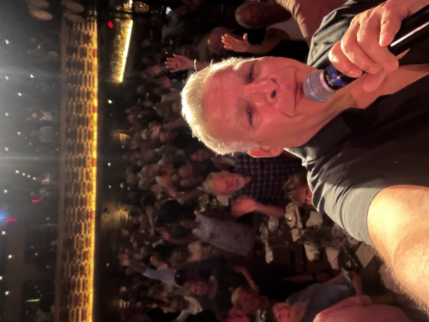 Jim DeRosa taking a selfie on stage with the full audience visible